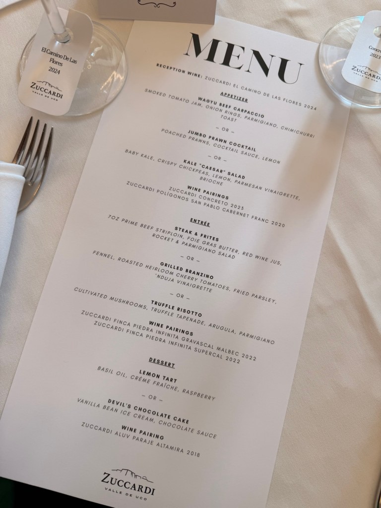 A printed menu featuring a selection of appetizers, entrees, and desserts for a dining event, with wine pairings listed for each course.